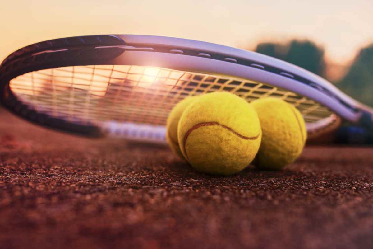 Racchetta e palline da tennis sul campo in terra rossa